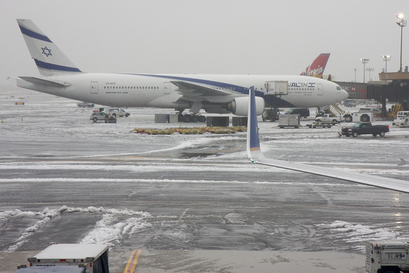 An El Al 777-200 parked at the snowy EWR Terminal B.