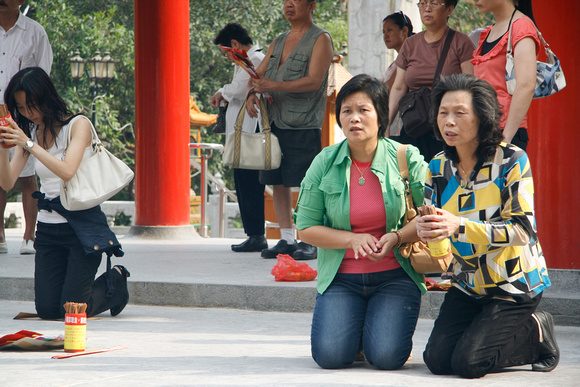 Worshippers shake a bamboo cup with fortune sticks until one falls out.