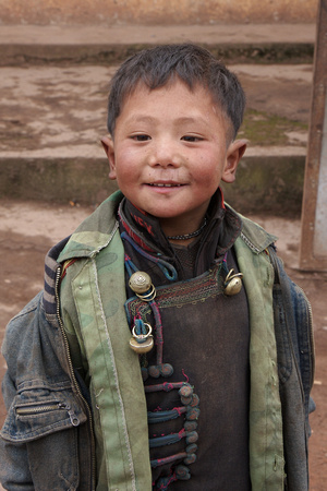 Traditional Yi clothings and ornaments underneath the jean jacket and camouflage.